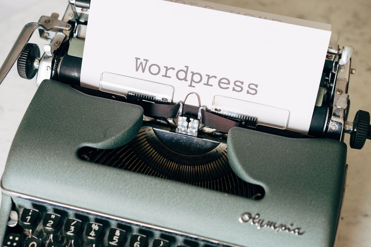 Gros plan sur une machine à écrire vintage avec une feuille affichant WordPress dans un style rétro.
